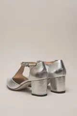 Sandalia de cuero color bordó, con acabado charolado, punta fina y tacón cuadrado de 5 cm. Presenta una tira en forma de T sobre el empeine y una correa con hebilla alrededor del tobillo.