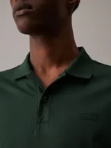 Chomba verde oscuro de algodón orgánico, corte slim, cuello clásico con solapa de dos botones, manga corta, puños de punto, aberturas laterales y logo tonal de Calvin Klein en el pecho.