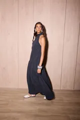 Vestido largo negro de crepe texturado con escote halter, cuello alto con volados y diseño holgado.