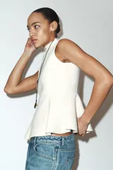 Top de punto sin mangas con cuello subido y diseño entallado con bajo en evasé tipo peplum.