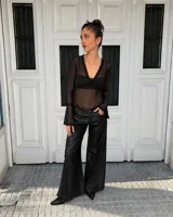 Body de tul transparente color negro, de manga larga con terminación acampanada y detalles de encaje en el escote en V y en los puños.