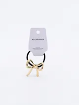 Colero de pelo con elástico negro y aplique de moña dorada.