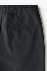Pantalón tipo jogger de vestir con pliegues frontales y traseros, cintura elástica con cordón de ajuste, bolsillos laterales al bies y bolsillos traseros insertados. Presenta un corte slim fit entallado.