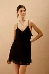 Vestido corto negro con escote en V, breteles finos ajustables y volados en el frente. Presenta espalda descubierta con lazos y ajuste elástico en la cintura.