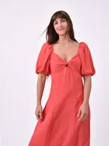 Vestido midi de color negro, con escote corazón, detalle de nudo en el centro del busto y mangas cortas abullonadas. Presenta un corte entallado en la parte superior y falda con caída fluida.