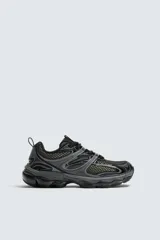 Zapatillas deportivas tipo running, color gris y negro, con suela de goma con volumen y diseño irregular.