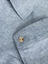 Blazer azul de lino con corte slim fit, solapa clásica, cierre con botones y bolsillo en el pecho.