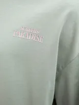 Camiseta verde con estampado de palmera, olas y texto "Gold Coast Surfers Paradise".