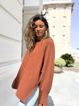 Sweater de punto color moka, con diseño oversize, cuello redondo, costura central vertical y puños acanalados.