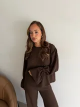 Buzo de textura arrugada color marrón chocolate, con cuello redondo y mangas largas con puños acampanados y fruncidos.