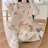 Conjunto de pijama de dos piezas confeccionado en plush suave, compuesto por una remera de manga larga y pantalón largo. Presenta un diseño estampado de duraznos sobre fondo color crema.