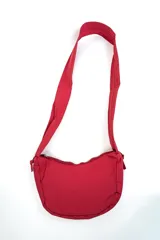 Bandolera color rojo, de diseño curvado y suave, con cierre superior y correa ancha ajustable para llevar al hombro o cruzada.