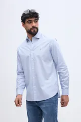 Camisa de manga larga fit semi slim color celeste, con cierre frontal de botones y cuello camisero clásico.