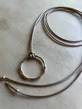 Gargantilla con cordón gris y dije circular de plata.