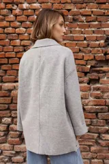 Tapado de paño color rosado, de corte oversized y diseño cruzado. Presenta solapas clásicas, mangas largas con puños vueltos y amplios bolsillos delanteros. Cierre frontal con un botón visible.