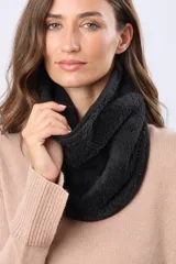 Cuello reversible de polar y sherpa color negro, con pequeño aplique de cuero sintético con logo grabado.