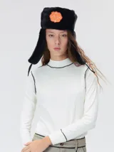 Polera de manga larga confeccionada en tela rib color bordó, con cuello alto y hombreras. Presenta costuras a la vista con pespuntes en hilo de color contrastante en el cuello, puños, hombros y ruedo.