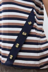 Remera de algodón con estampado de rayas horizontales en tonos azul marino, marrón y blanco. Presenta cuello redondo, mangas cortas con dobladillo y detalle de botones en el lateral inferior.