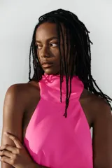 Vestido largo fucsia de cuello halter, espalda descubierta y cierre lateral con cremallera oculta en costura.