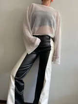 Pantalón largo de cuero sintético, corte recto, con diseño color block en blanco y negro.