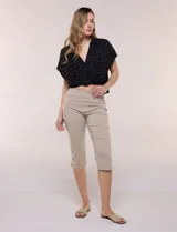 Pantalón capri blanco de tiro alto, corte entallado y silueta ajustada, con pretina ancha elastizada sin cierres, bolsillos simulados al frente y pequeños tajos en los ruedos.