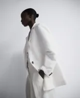 Blazer recta color blanco de lino europeo y viscosa responsable, con solapa, manga larga con hombreras, tres botones en puño, cierre de dos botones y bolsillos de vivo con solapa en delantero.