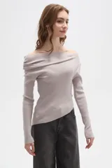 Sweater de punto acanalado color gris claro, con diseño de hombros descubiertos y cuello asimétrico drapeado. Presenta mangas largas y un corte ajustado al cuerpo.