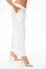 Pantalón palazzo blanco con estampado de hojas doradas, cintura alta con elástico y bolsillos laterales.