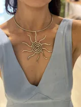 Collar tipo choker rígido plateado con un gran dije colgante en forma de sol estilizado con espirales en el centro.