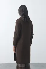 Cardigan de tejido de punto gris, con silueta larga, frente abierto, solapas clásicas y bolsillos aplicados en los laterales.