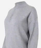 Suéter de punto color gris con cuello alto y medio cierre frontal. Presenta mangas largas con puños ajustados y una sutil aplicación de brillos en la parte frontal.