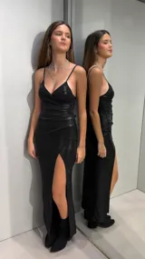 Vestido largo negro con brillo, de tirantes finos, escote en V cruzado y tajo pronunciado en la pierna.