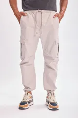 Pantalón tipo cargo jogger color gris claro, con cintura elástica ajustable mediante cordón, bolsillos laterales tipo cargo y puños elásticos en los tobillos.