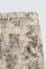 Pantalón de corte relajado confeccionado en algodón, con diseño de efecto lavado y estampado abstracto en tonos grises y beige. Presenta cinco bolsillos y cierre frontal con cremallera y botón.