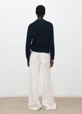 Sweater de punto color azul marino, con cuello redondo y mangas largas que presentan una línea blanca decorativa a lo largo de las costuras raglán y los puños.