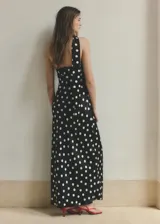 Vestido largo negro con estampado de lunares blancos, diseño asimétrico de un solo hombro y tejido fluido de poliéster. Incluye un fular a juego para el cuello.