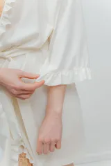 Bata kimono gris claro de algodón con volados en mangas y ruedo. Tiene mangas al codo y lazo de algodón para ajustar en la cintura.