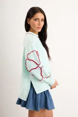 Buzo oversize de algodón con spandex, color verde menta, de manga larga con diseño de flores bordadas en rojo en las mangas y cuello redondo.