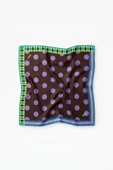 Pañuelo cuadrado de satén con estampado de lunares violetas sobre fondo marrón. Presenta un borde decorativo con patrón geométrico de rombos en tonos turquesa, verde lima y marrón, finalizado con líneas paralelas en los bordes.
