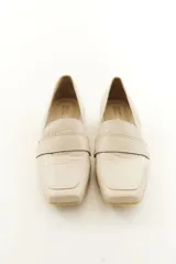 Mocasines de cuero vacuno color beige con textura efecto cocodrilo, punta cuadrada y taco bajo.