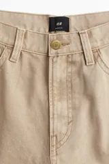 Pantalón de lona color beige, de corte holgado con pierna ancha y cinco bolsillos.