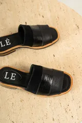 Sandalias planas de cuero marrón con tira ancha sobre el empeine. La plantilla es de cuero con la inscripción "LE".