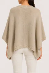Poncho de punto color beige con diseño de botones frontales, cuello redondo y mangas cortas integradas.