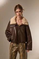 Chaqueta de cuero sintético color marrón, con cuello de piel sintética en tono crema, cierre frontal y diseño holgado.