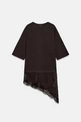 Camiseta de algodón de corte regular, color marrón oscuro o negro, con cuello redondo y manga corta. Presenta un bajo asimétrico con aplicación de encaje negro a tono.