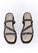 Sandalia de cuero negro con tiras cruzadas decoradas con strass brillante. Cuenta con una base de plataforma baja de 3,5 cm y plantilla acolchada.