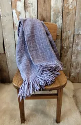 Ruana de lana merino tejida en telar, con diseño de rayas verticales en tonos crudo y rojizo, y terminación de flecos en el ruedo.
