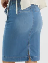 Falda de denim en lavado azul medio con efecto de desgaste localizado, de silueta tubo y largo a la rodilla. Presenta tiro medio-alto, pretina con trabillas, cierre frontal con cremallera y botón metálico, bolsillos frontales y costuras verticales que estructuran la prenda.