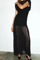 Vestido midi negro de cuello alto y sin mangas, con detalle drapeado en la parte superior y falda plisada. Incluye forro interior con tirantes finos ajustables y cierre lateral con cremallera oculta.