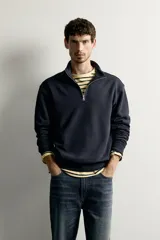 Sudadera negra de corte regular fit, con cuello subido, cierre frontal de cremallera corta y acabados en rib elástico en puños y cintura.